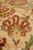 Close-up of a gold and rust palmette with mint petals on soft beige wool pile