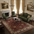 Green sofa and armchairs framing a red floral Oriental rug on dark hardwood living room floor