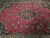 Close-up of crimson field, vine scrollwork and lobed black central medallion in fine wool pile