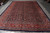 Hand-knotted 10x13 Persian rug laid flat with ivory cotton fringe along the near end