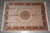 Overhead view of 10x14 Tabriz design wool rug on grey tile, gold and burgundy