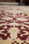 Low-angle close-up of hand-knotted wool pile showing burgundy, cream and gold floral drawing
