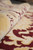 Rolled edge close-up showing dense wool pile, ivory ground and burgundy scrollwork