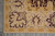 Corner section of the rug on grey floor showing layered borders and burgundy field edge