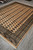 9 by 12 hand-knotted wool Bokhara rug on grey tile with ivory fringe