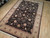Angled showroom view of the 6x9 black and tan hand-knotted wool and silk floral rug