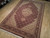 Angled view of 6x9 burgundy medallion rug showing beige spandrels and floral main border