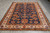 6'10 x 10'2 hand-knotted Kazak rug displayed on grey tile showroom floor, cream main border