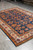 Perspective shot showing the silky wool pile and ivory floral border of this 7x10 Kazak rug