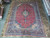 Red and blue Persian Kashan rug laid flat showing balanced medallion and wide floral border