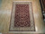 6'2" x 9' Oriental rug displayed flat on light wood showroom floor, burgundy field