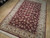 Angled showroom view showing ivory multi-border, floral vinework and dense wool pile sheen