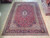 9'9" x 13'4" Persian Kashan rug on wood floor showing deep red field