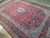 Angled view of hand-knotted wool Kashan rug, navy border and dense floral vinework throughout