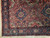 Corner detail showing navy blue main border, octagonal rosettes and cross-shaped star motifs