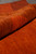 Rolled edge of the wool rug showing pile depth, flexible handle and rich rust coloration