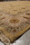 Angled corner of 9x13 Oriental area rug showing layered borders and soft gold outer edge
