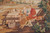 Detail of picnic bench scene with wine bottles, seated figures and garden foliage