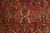Close up of gold vine work, sage green palmettes and small rosette on red wool