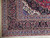 Corner detail of black palmette border, ivory spandrel, blue guard stripes and white fringe