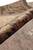 Rolled edge of the rug showing pile thickness and painterly rust and beige leaf scrolls