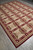 9 by 12 flat weave rug angled on grey tile showing burgundy grid and olive squares