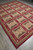 Angled view showing olive and beige panel grid with deep red lattice and striped outer border
