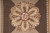 Macro of hand stitched rosette showing cream, tan and brown shading with raspberry ring center