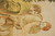 Close detail of two seated figures in cream robes against the ivory tapestry field