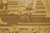 Woven detail of a small spaniel on stone steps beside sandaled feet and green grass