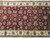 Close-up of olive, gold and ivory palmettes scrolling across the claret red wool field