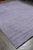 9x12 lavender wool rug viewed lengthwise on grey plank flooring in natural daylight