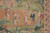 Close-up of woven figures in period dress gathered on an apricot and green hillside clearing