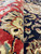 Side view of pile height contrasting crimson border wool against the deep black floral field