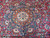 Center medallion close-up with ivory rosette, orange cartouche frame and turquoise blossoms on red ground