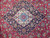 Close-up of ivory and indigo lobed medallion with rose and olive florals on red field