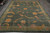 Hand-knotted Nepal wool rug flat on grey tile, plain green border framing large floral vines