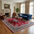 Red Kerman rug anchoring a living room with blue tufted sofa, leather chairs and fireplace