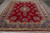 Overhead view of hand-knotted Kerman rug showing scalloped blue frame and dense floral bouquets