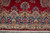 Border close-up showing arched floral cartouches, ivory blossoms and fringe along the rug end