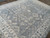 Angled view of dusty blue field with ivory stepped medallions and soft tonal wool pile