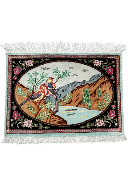 A Persian Qum silk rug with a pictorial design of two birds on a branch, surrounded by a floral border and fringe edges.