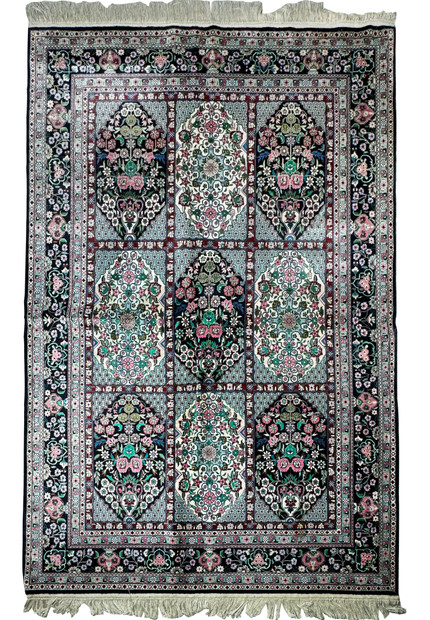 Close-up of the intricate floral and geometric patterns on a Persian Qum silk rug with shimmering silk threads