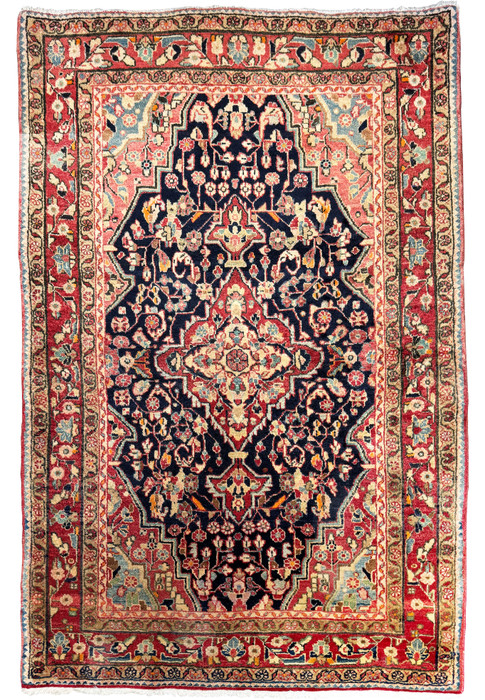 A full view of a 4'3" x 6'5" Vintage Persian Sarough Rug with intricate floral designs and a deep navy blue central field surrounded by borders of cream, crimson, and sage.