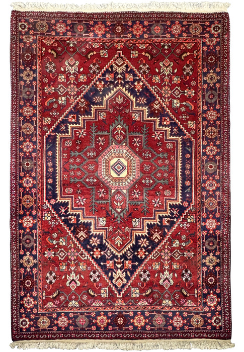 Full view of a 3'4" x 5'1" Persian Gholtogh Rug displayed on a flat surface. The rug's dominant red field is embellished with intricate floral and geometric patterns, framed by detailed navy blue and pastel borders. This hand-knotted wool rug exemplifies the exquisite artistry and durability of traditional Persian rugs.
