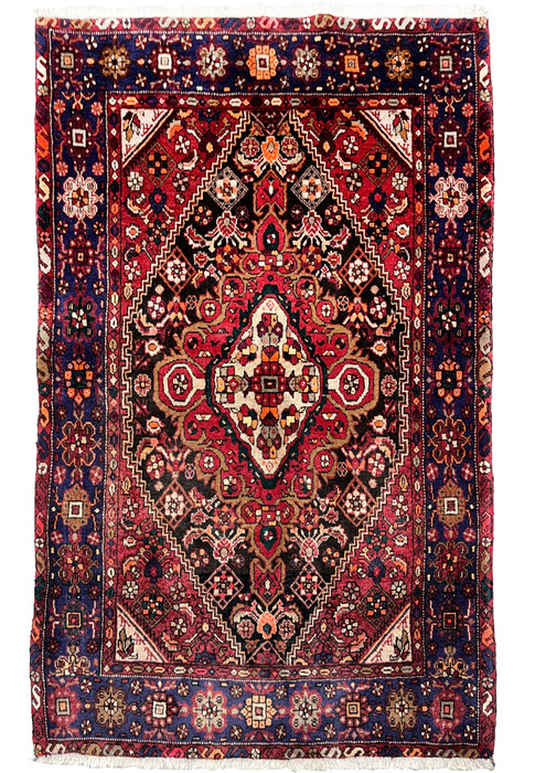Full view of a 3'4 x 5'5 Persian Gholtogh rug with a deep red field, navy border, bold tribal medallion, and dense hand-knotted wool texture