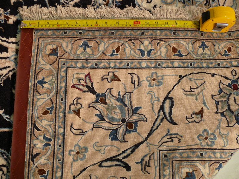 This picture displays the back of a Persian Nain wool and silk rug, measuring 8' x 11'. While most rugs are beautiful on their front side, this image showcases the impressive craftsmanship and attention to detail that goes into the making of this rug, even on its backside. The rug's exceptional quality is evident in the tight weave and the neatness of the knotting. This rug is a true work of art, from whichever angle you look at it.