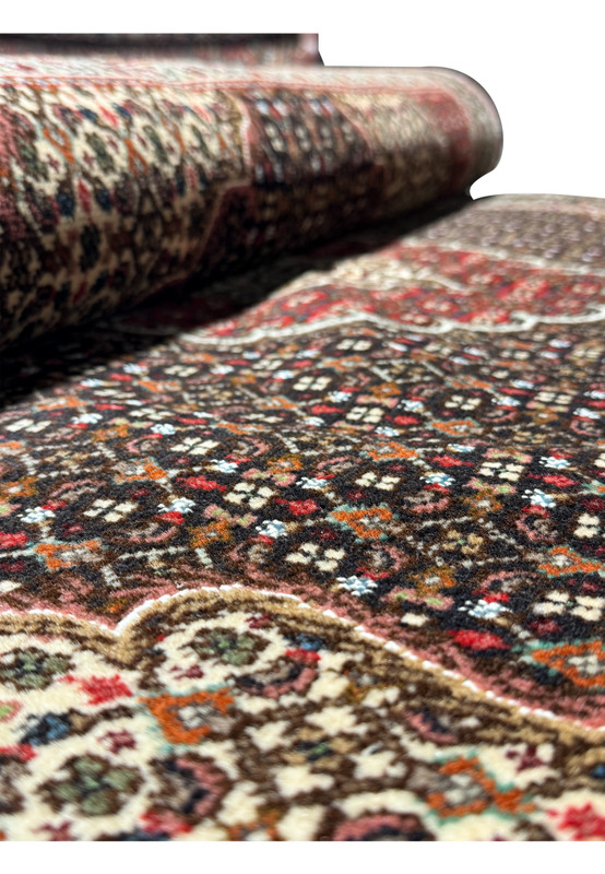 Close-up showing the intricate pattern and vibrant colors of a Persian Tabriz Mahi rug, with a focus on the dark brown field and cream accents