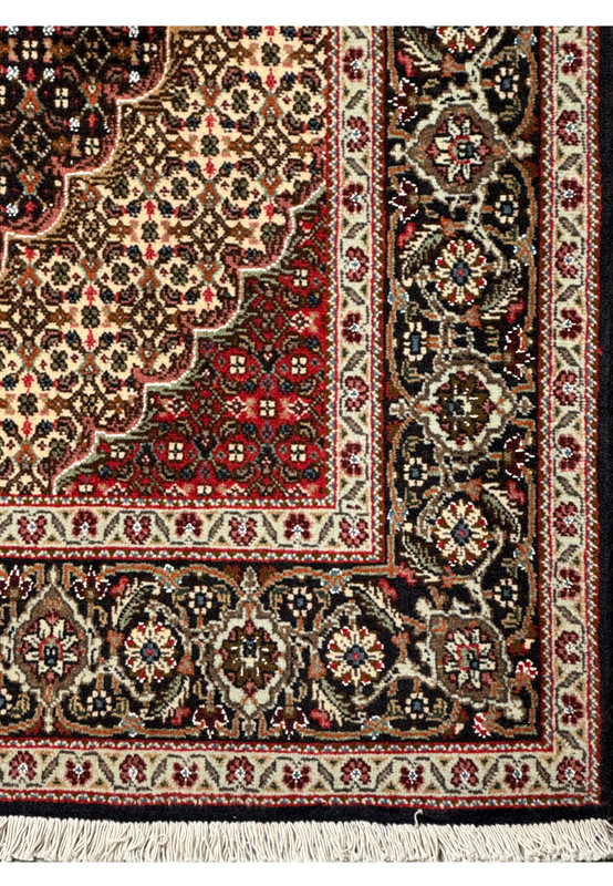 A Persian Tabriz Mahi rug's border detailed with navy blue, olive green, pink, and cream designs on a dark brown background