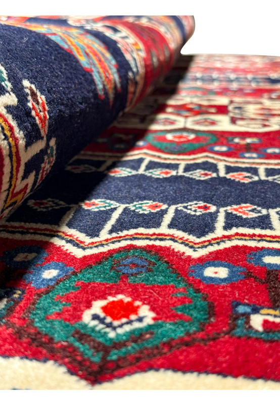 Perspective shot of a Persian Qashqai rug with a focus on the texture and weave, showcasing the vibrant colors and traditional design